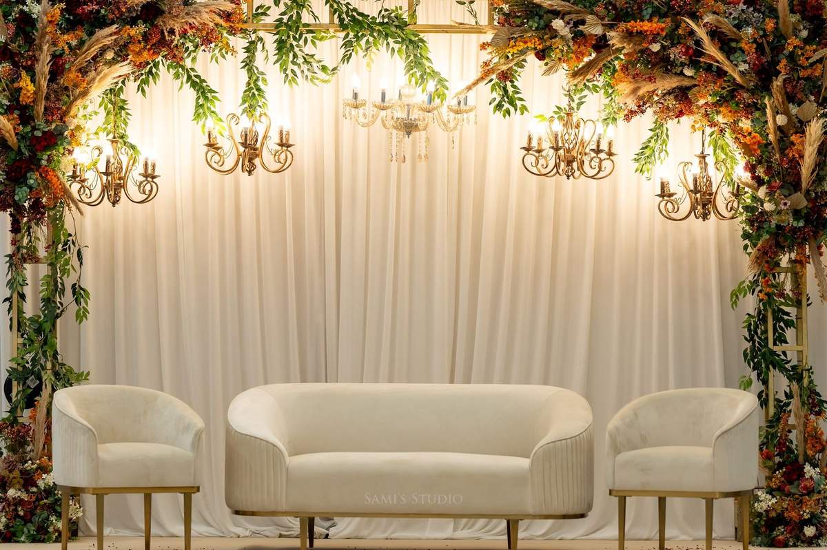 White drape stage with chandeliers and cream seating