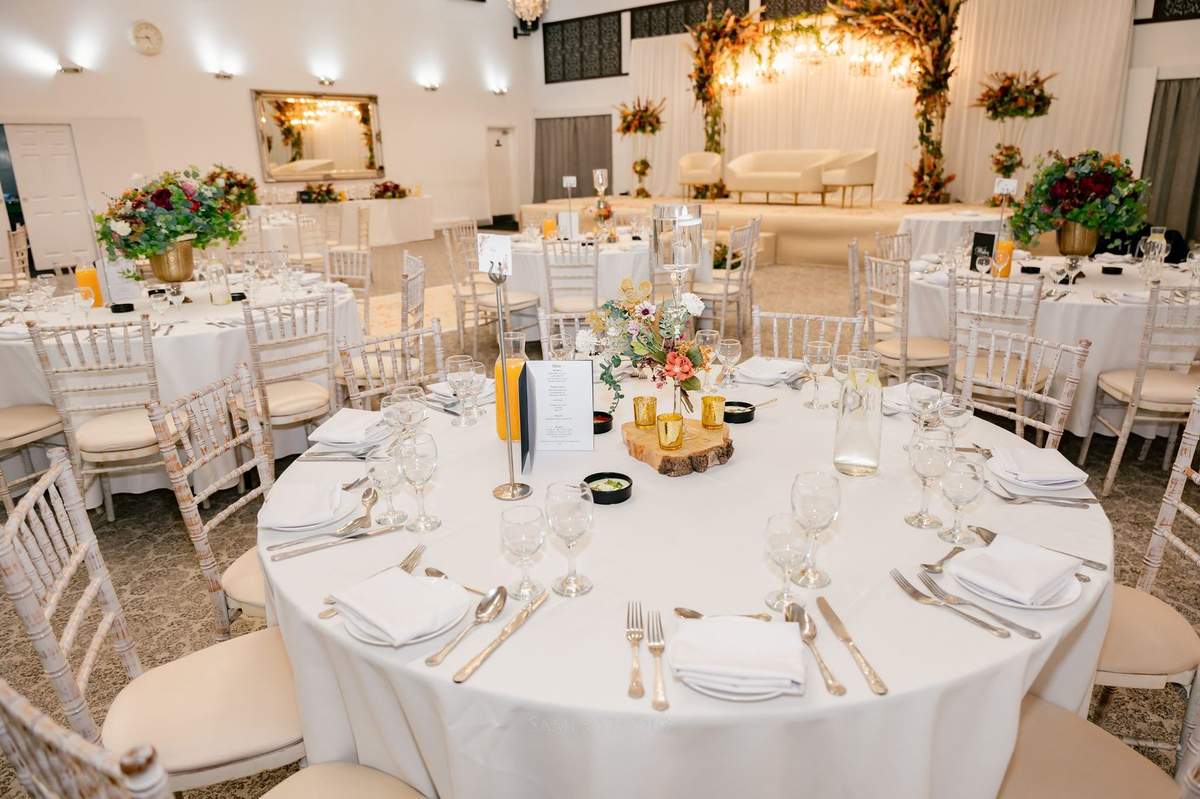 White round tables set for dinner, facing the stage